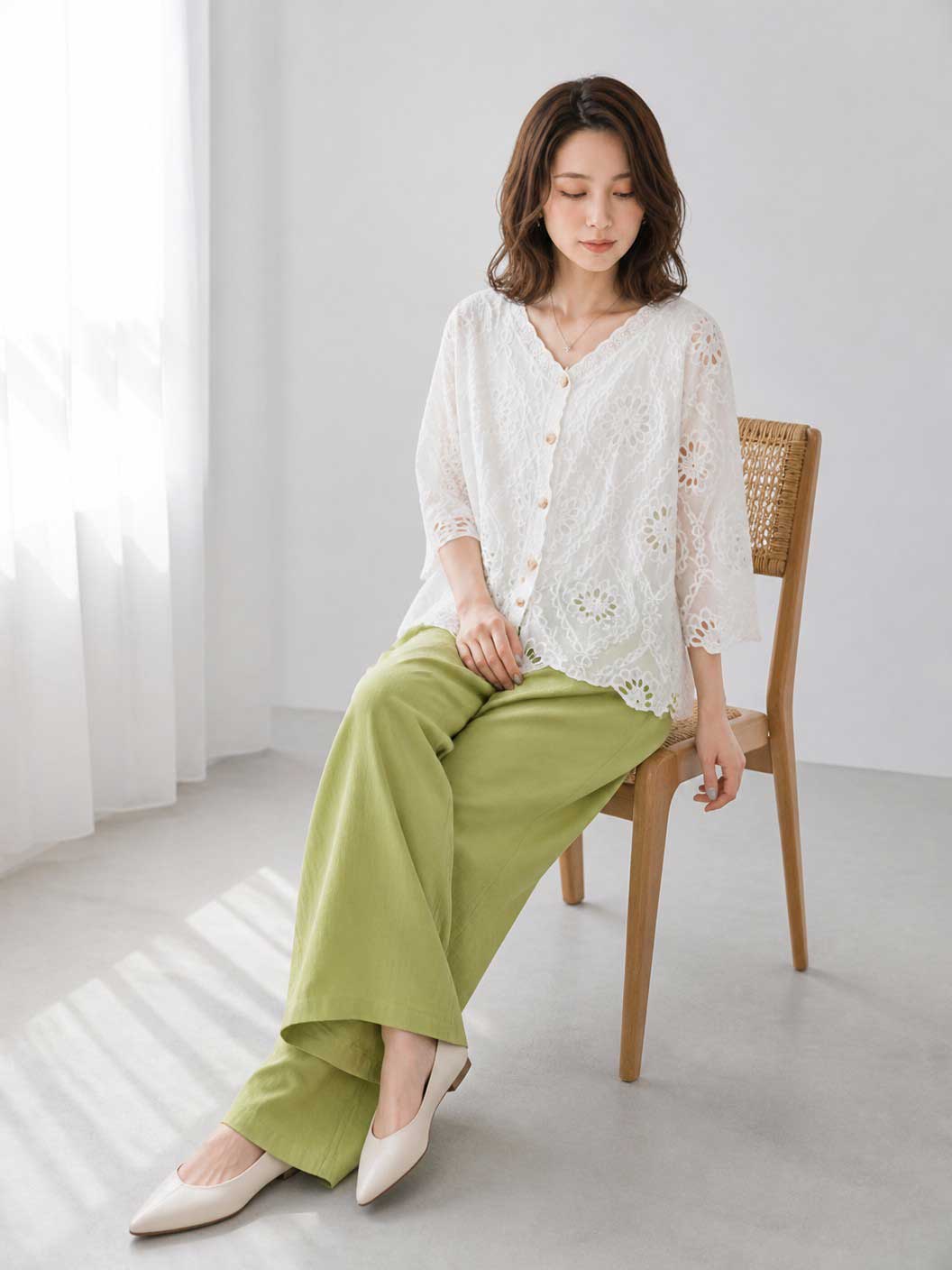 Mikonosublue Storeの白いコットン製カットワーク刺繍ブラウス。Vネックと七分袖で、涼しげな透け感のあるデザイン。