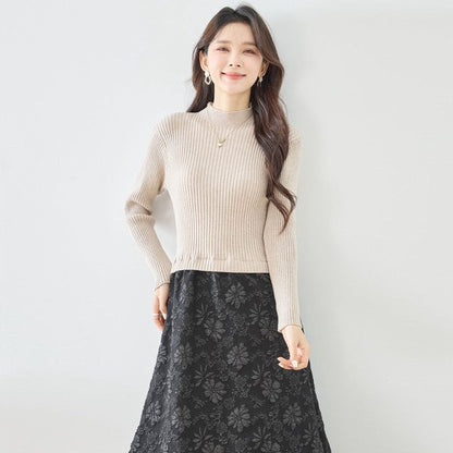 Mikonosublue Storeのベージュのリブニットと黒のふくれジャガードスカートをドッキングした長袖ワンピースを着た女性