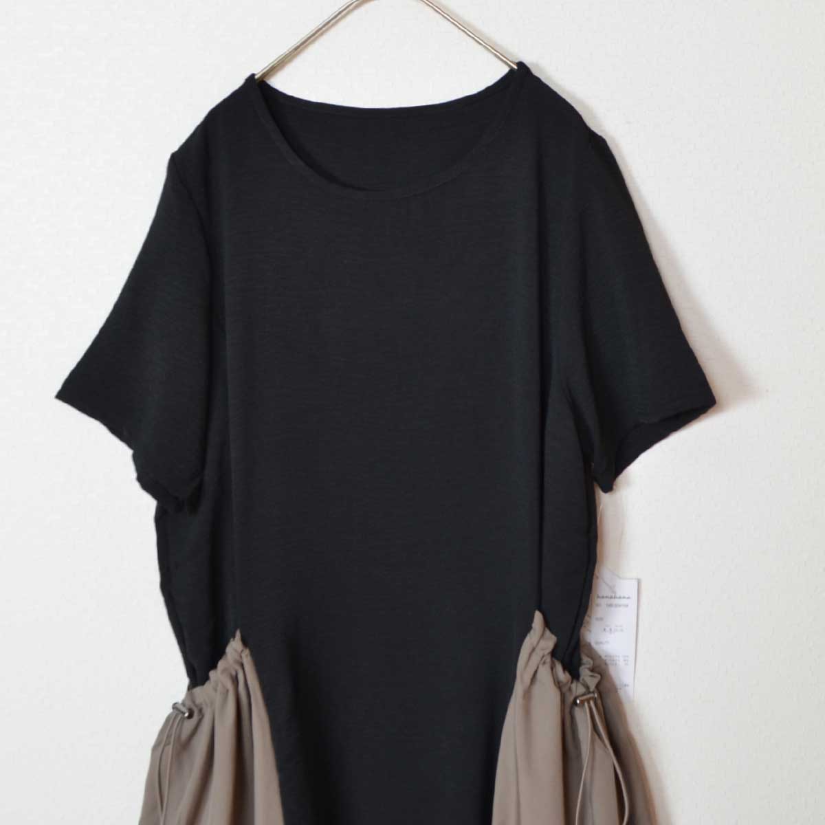 Mikonosublue Storeの黒い半袖ワンピース。ドロスト付きの大きな異素材ポケットが特徴のゆったりとしたデザイン。