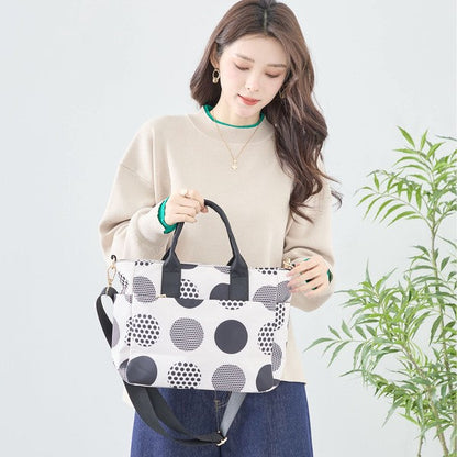 Mikonosublue Storeのランダムな大ドット柄が特徴的なポリエステル製2WAYハンドバッグを持つ女性