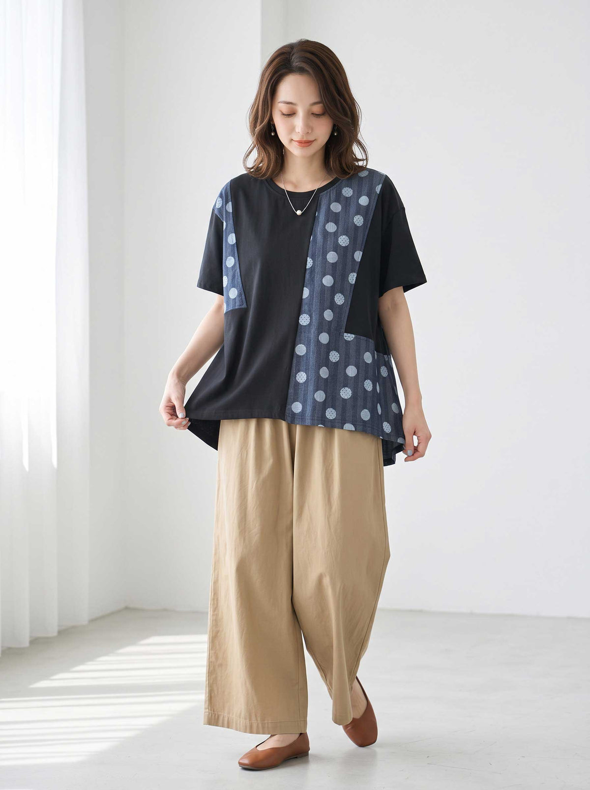 Mikonosublue Storeの黒い異素材切り替えトップス。ドット柄と無地のパッチワークデザインで、ゆったりとしたAラインの半袖カットソー。