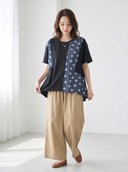 Mikonosublue Storeの黒い異素材切り替えトップス。ドット柄と無地のパッチワークデザインで、ゆったりとしたAラインの半袖カットソー。