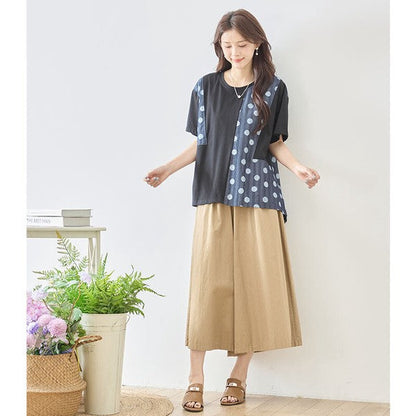 Mikonosublue Storeの黒い無地とドット柄の異素材切り替え半袖トップスを着用した女性