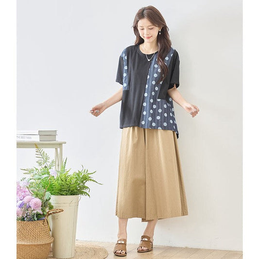 Mikonosublue Storeの黒い無地とドット柄の異素材切り替え半袖トップスを着用した女性