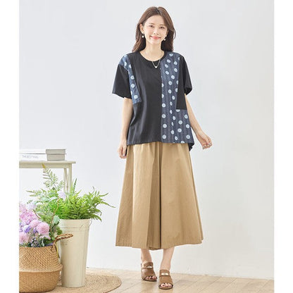 Mikonosublue Storeのドット柄と無地の異素材切り替え半袖トップスを着用した女性。ゆったりとしたAラインシルエットで体型カバーも叶う夏らしいカジュアルスタイル。