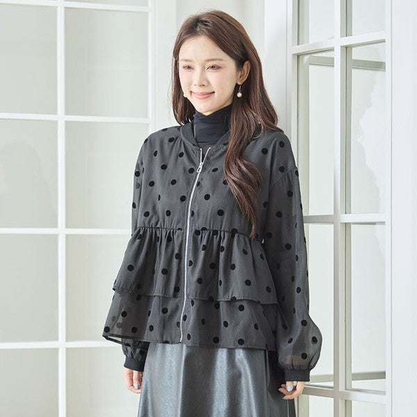 Mikonosublue Storeの黒いドットフロッキー柄シアー素材ティアードフリルジップアップブルゾンを着用した女性