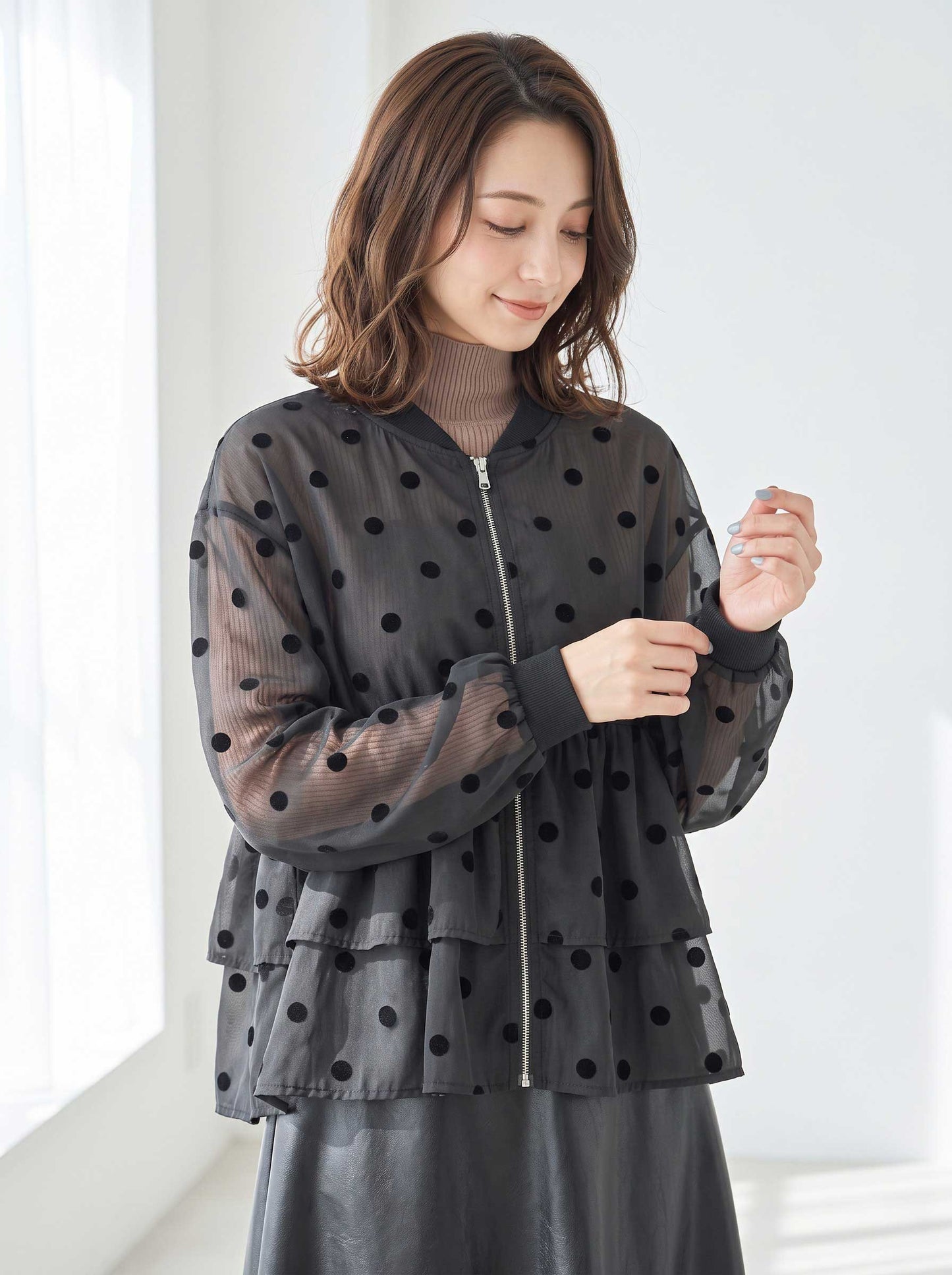 Mikonosublue Storeのドットフロッキー柄シアー素材ティアードフリルジップアップブルゾンを着用した女性