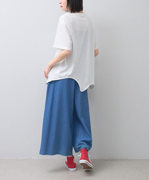 Mikonosublue Storeのフラワーとドット柄がプリントされた涼しげなブルーのワイドパンツを履いた女性のバックスタイル