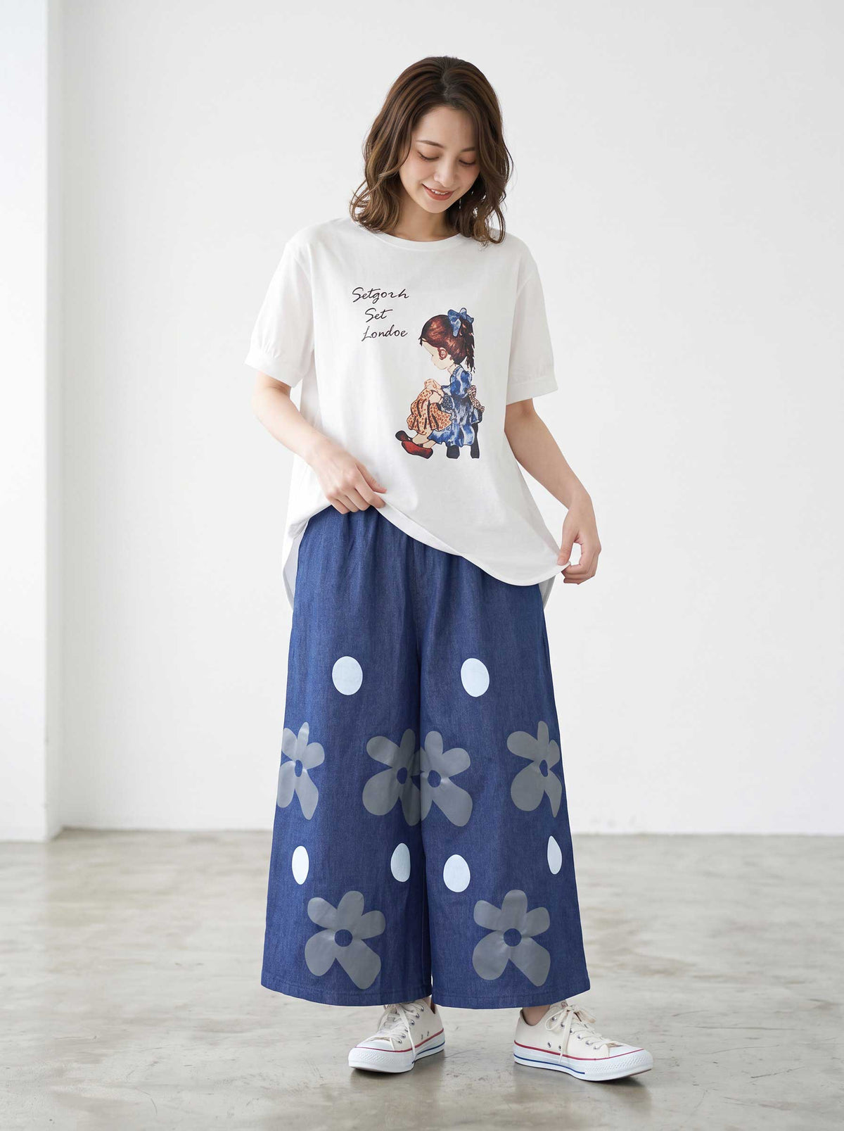 Mikonosublue Storeのフラワーとドット柄がプリントされたデニムライクなワイドパンツを着用した女性