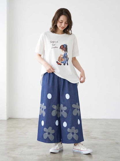 Mikonosublue Storeのフラワーとドット柄がプリントされたデニムライクなワイドパンツを着用した女性