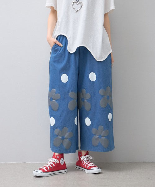 Mikonosublue Storeのフラワーとドット柄がプリントされたブルーの綿混ワイドパンツ。ゆったりとしたシルエットで夏に涼しいカジュアルなデザイン。