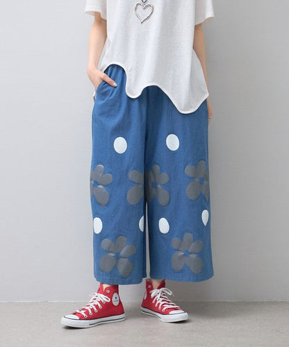 Mikonosublue Storeのフラワーとドット柄がプリントされたブルーの綿混ワイドパンツ。ゆったりとしたシルエットで夏に涼しいカジュアルなデザイン。