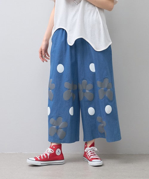 Mikonosublue Storeのフラワーとドット柄がプリントされたブルーの綿混ワイドパンツ。ゆったりとしたシルエットで夏に涼しいカジュアルなデザイン。