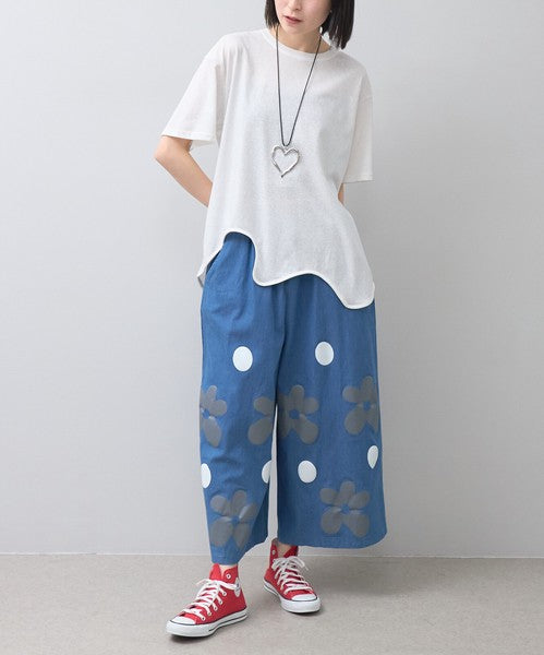 Mikonosublue Storeのフラワーとドット柄がプリントされたブルーのワイドパンツを履いた女性