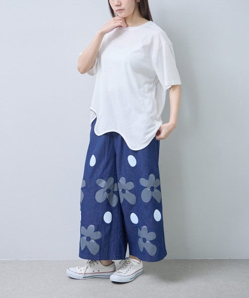 Mikonosublue Storeのフラワーとドット柄がプリントされたデニムライクなワイドパンツを着用した女性