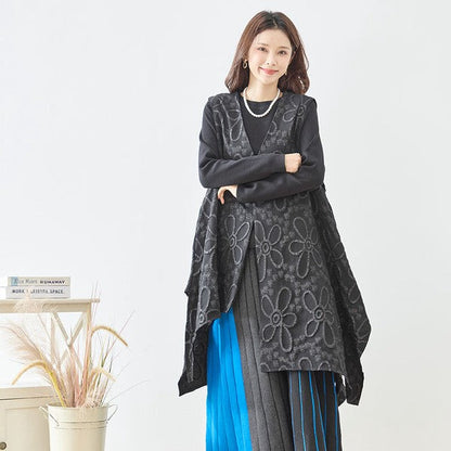 Mikonosublue Storeの立体的な花柄ふくれジャガード生地を使用した黒のアシンメトリーロングベストを着用した女性