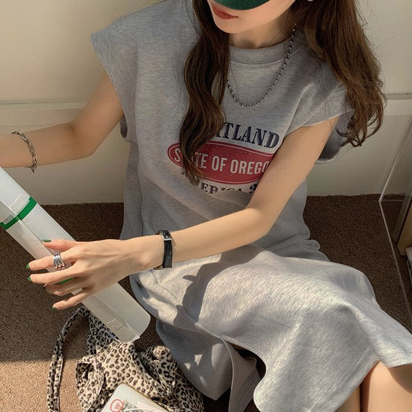 Mikonosublue Storeのグレーのロゴプリント入りフレンチスリーブTシャツワンピース。ゆったりとしたシルエットでサイドスリット入り。