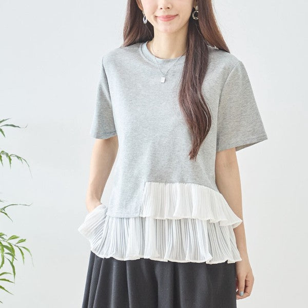 Mikonosublue Storeのグレーの半袖Tシャツ。裾にホワイトの異素材アシンメトリープリーツフリルをあしらった体型カバーができるフェミニンなトップス。