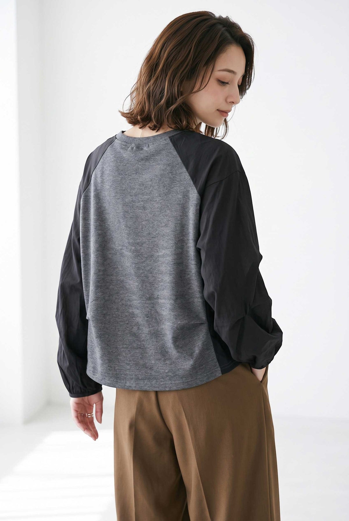 Mikonosublue Store grey and black raglan pullover with voluminous pleated sleeves worn by a woman
