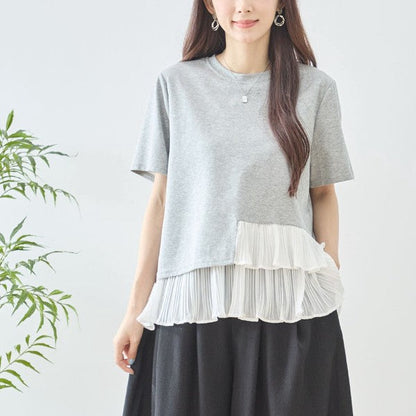 Mikonosublue Storeのグレーの半袖Tシャツ。裾に白いシフォンのアシンメトリーな2段ティアードプリーツフリルをあしらった、体型カバーができるフェミニンなデザイン。