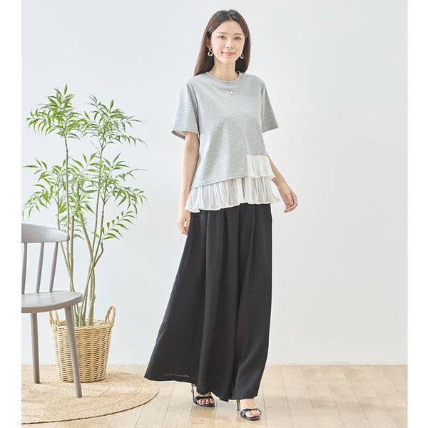 Mikonosublue Storeのグレーの半袖Tシャツ。裾に白いアシンメトリーなプリーツフリルをあしらった異素材切り替えデザインで、体型カバーも叶うフェミニンなトップス。