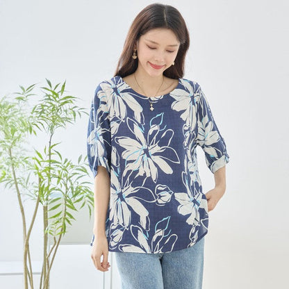 Mikonosublue Storeのネイビー地に白い大きな花柄がプリントされた、ゆったりとした綿100%のドルマントップスを着た女性