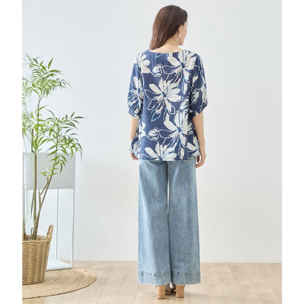 Mikonosublue Storeのネイビー地に白い大きな花柄がプリントされた綿100%のゆったりとしたドルマン袖トップスを着用した女性のバックスタイル