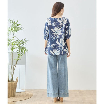 Mikonosublue Storeのネイビー地に白い大きな花柄がプリントされた綿100%のゆったりとしたドルマン袖トップスを着用した女性のバックスタイル