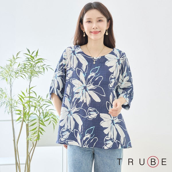 Mikonosublue Storeのネイビー地に白い大きな花柄がプリントされた綿100%のゆったりとしたドルマン袖トップスを着た女性