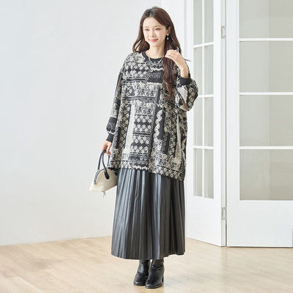 Mikonosublue Storeのモノトーン花柄パッチワーク風チュニックを着用した女性。ゆったりとしたドロップショルダーの長袖プルオーバーに黒のプリーツスカートを合わせた秋冬コーデ。
