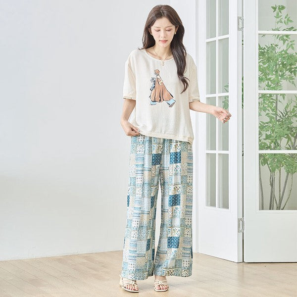Mikonosublue Storeのファッションイラストプリント半袖トップス。ゆったりとしたドロップショルダーと配色リブが特徴のベージュのカットソーを着用した女性。
