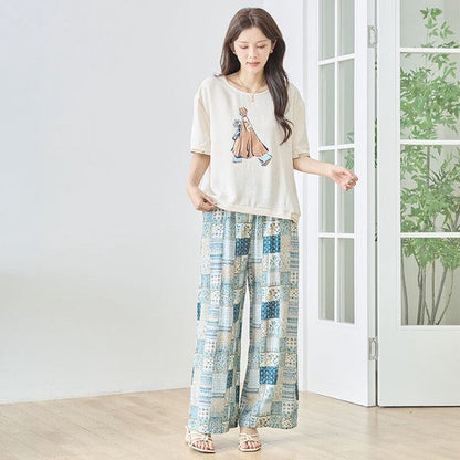 Mikonosublue Storeのファッションイラストプリント半袖トップス。ゆったりとしたドロップショルダーと配色リブが特徴のベージュのカットソーを着用した女性。