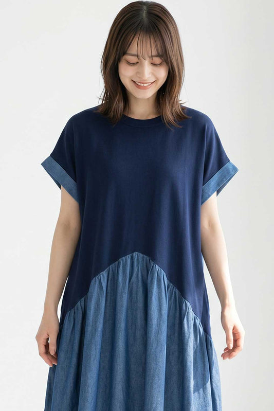 Mikonosublue Storeのインディゴ染め天竺と布帛を組み合わせた、斜め切替ギャザーが特徴のロング丈ワンピースを着用した女性
