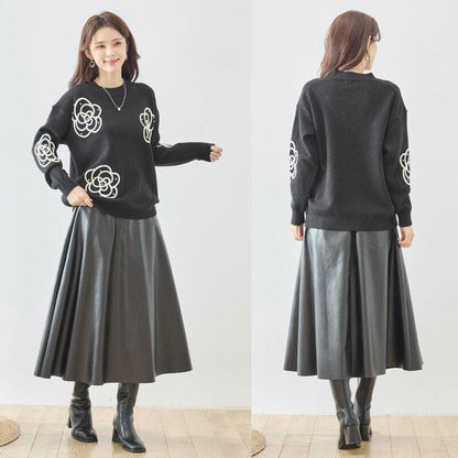 Mikonosublue Storeの黒いニットプルオーバー。カメリア柄のコード刺繍とパール、ビジューが施され、フレアスカートと合わせた上品なコーディネート。