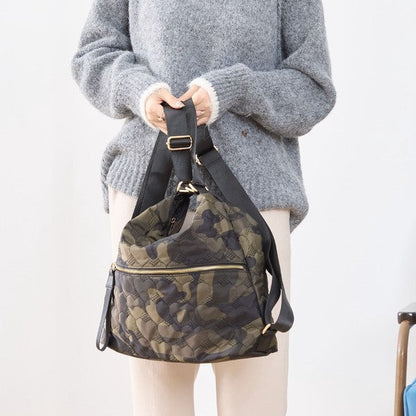 Mikonosublue Storeのハートキルティングが施された迷彩柄ショルダーバッグを肩に掛ける女性