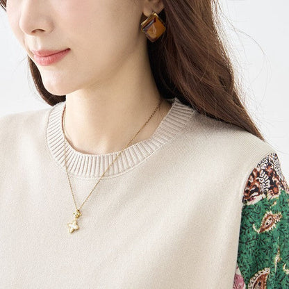 Mikonosublue Storeのベージュニットとパッチワーク柄の異素材ドッキングワンピースを着用した女性のクローズアップ