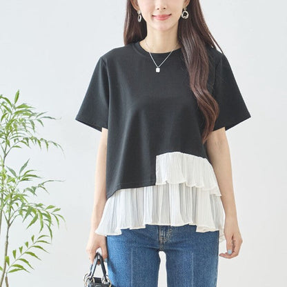 Mikonosublue Storeの黒い半袖Tシャツ。裾に白いアシンメトリーなプリーツフリルが施された異素材切り替えデザインで、体型カバーも叶うフェミニンなトップス。