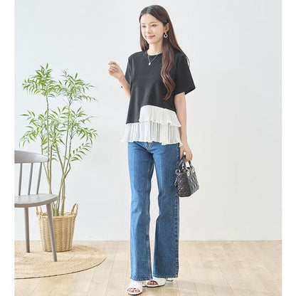 Mikonosublue Storeの黒い半袖Tシャツ。裾に白いアシンメトリーな2段ティアードプリーツフリルをあしらった異素材切り替えデザインで、デニムと合わせた大人カジュアルな着こなし。