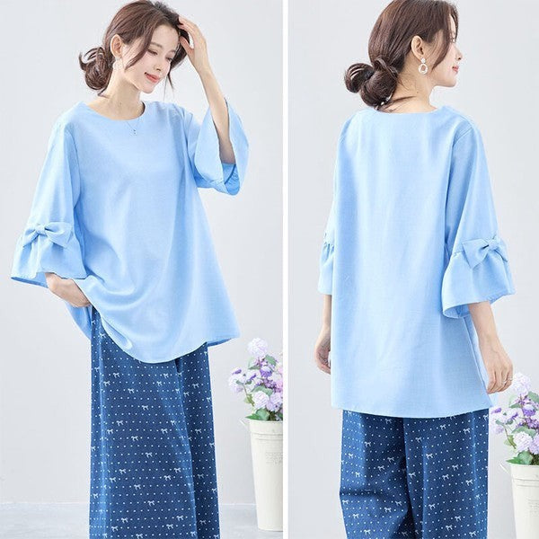 Mikonosublue Storeの袖リボン付きライトブルーの七分袖Aラインチュニックブラウス。ゆったりとしたシルエットで体型カバーも叶うフェミニンなデザイン。