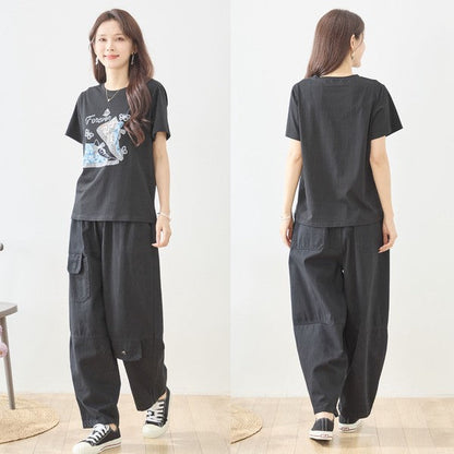 Mikonosublue Storeのラインストーンと異素材パッチワークのスニーカー柄が施された黒の半袖Tシャツを着用した女性