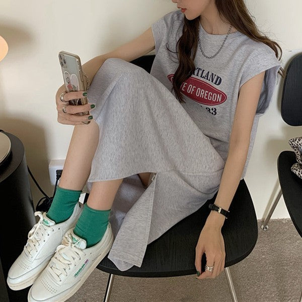 Mikonosublue Storeのロゴプリント入りグレーのフレンチスリーブTシャツワンピース。サイドスリット入りでゆったりとしたシルエット。