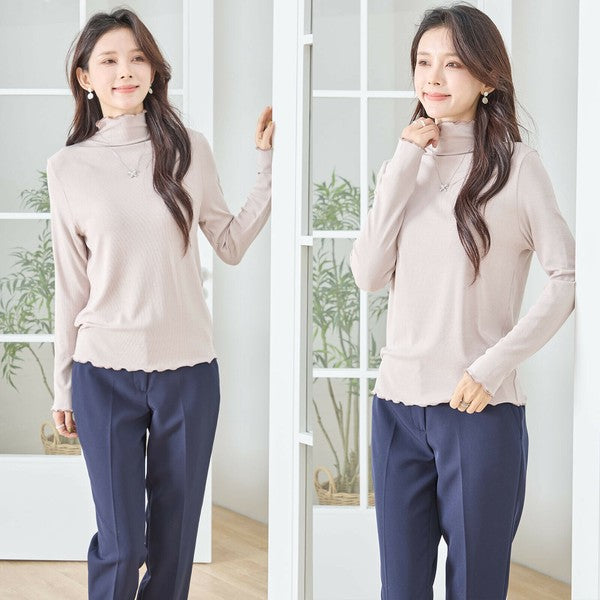 Mikonosublue Storeのベージュのメロウフリルハイネック長袖リブカットソーを着用した女性