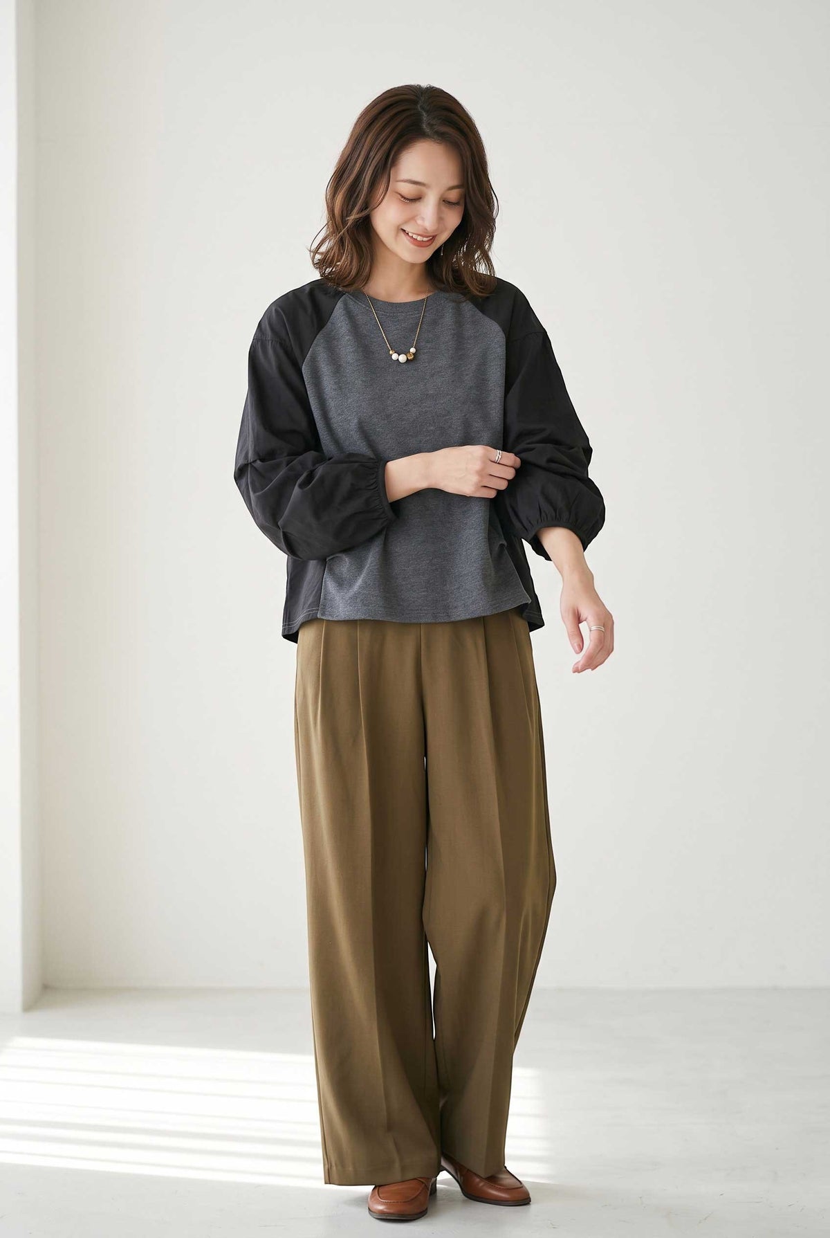 Mikonosublue Store grey and black mixed-material pullover with voluminous raglan tuck sleeves worn with brown trousers