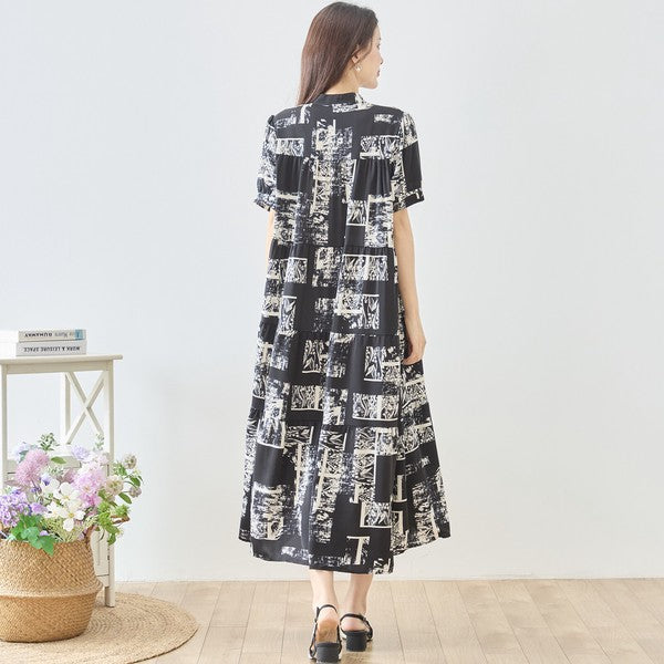 Mikonosublue Storeのモノトーンアート柄ティアードマキシワンピース。バンドカラーの半袖で、ゆったりとしたシルエットが特徴のきれいめな一着。