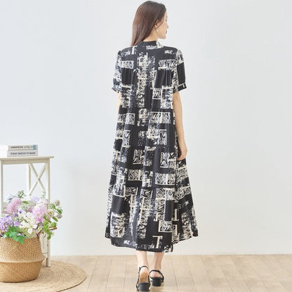 Mikonosublue Storeのモノトーンアート柄ティアードマキシワンピース。バンドカラーの半袖で、ゆったりとしたシルエットが特徴のきれいめな一着。