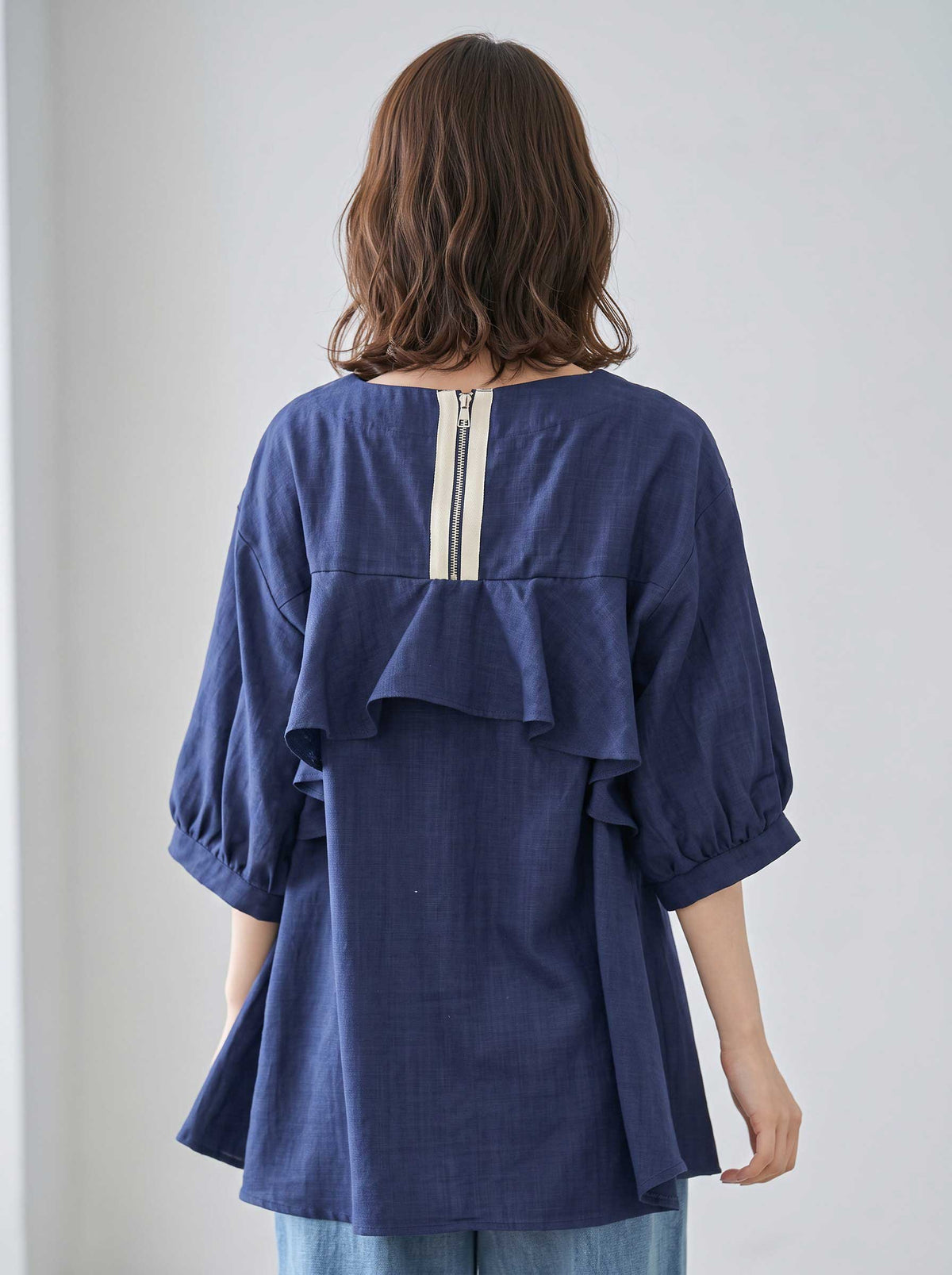 Mikonosublue Storeのバックフリルとファスナーが特徴的なネイビーの5分袖Aライントップス。ゆったりとしたシルエットで二の腕をカバーする夏用ブラウス