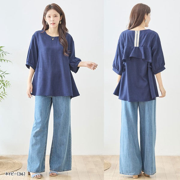 Mikonosublue Storeのバックフリルが特徴的なネイビーの5分袖Aライントップスを着用した女性