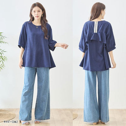 Mikonosublue Storeのバックフリルが特徴的なネイビーの5分袖Aライントップスを着用した女性