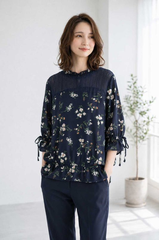 Mikonosublue Storeのネイビー花柄ジョーゼットブラウス。デコルテのレースと袖口のリボンが上品な七分袖ペプラム風トップス。