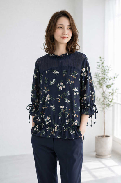 Mikonosublue Storeのネイビー花柄ジョーゼットブラウス。デコルテのシアーレースと袖口のリボンが上品な七分袖トップス。